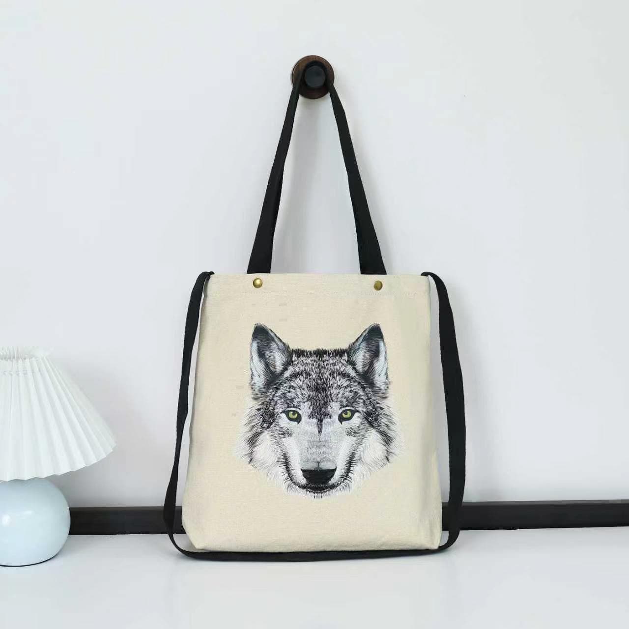Gahumi cream canvas bag with black handles, a shoulder strap and a wolf-head design